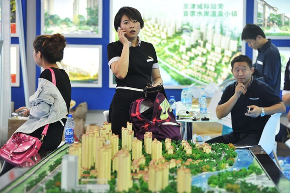 Prospective homebuyers look at a residential property project model at a real estate exhibition in Beijing. (Photo provided to China Daily)