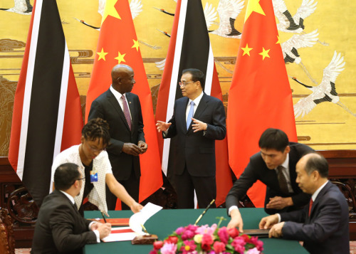 Premier Li Keqiang and visiting Prime Minister Keith Rowley of Trinidad and Tobago witness the signing of documents on cooperative initiatives in the Great Hall of the People in Beijing on Tuesday. (FENG YONGBIN/CHINA DAILY)