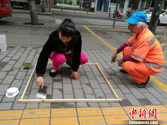 An inspector checks the road a cleaner has swept. (Photo/Chinanews.com)